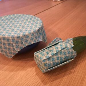 Foto zum vierten Schritt für ein selbstgemachtes Bienenwachstuch: Fertige Wachstücher auf Schüssel und angeschnittener Gurke