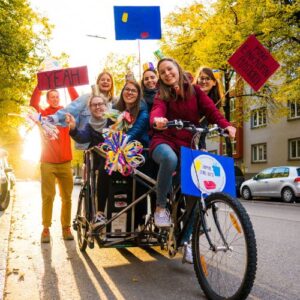 Foto des ursprünglichen Teams von „Einmal ohne, bitte“ mit Lastenrad und bunter Deko mit Verlinkung zur Seite „Über uns“