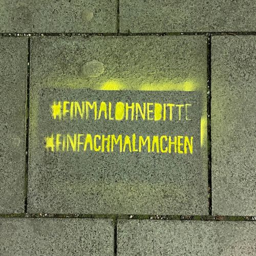 In Gelb auf den Gehweg gesprayte Hashtags „Einmal ohne, bitte“ und „Einfach mal machen“