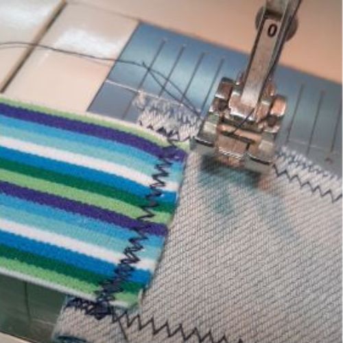 Foto zum dritten Schritt für eine selbstgenähte Bechermanschette: Jeansstoff und Hosengummi unter der Nähmaschine