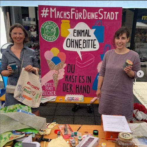 Foto von zwei Vertreterinnen des „Einmal ohne, bitte“-Teams Künzelsau an einem Aktionsstand mit Verlinkung zur Teamvorstellung